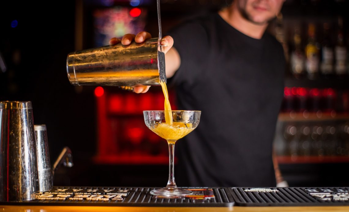 Barman versant un cocktail au shaker