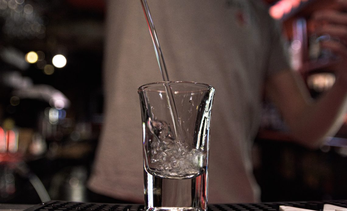 Shot de vodka servi par un bartender dans un bar de nuit